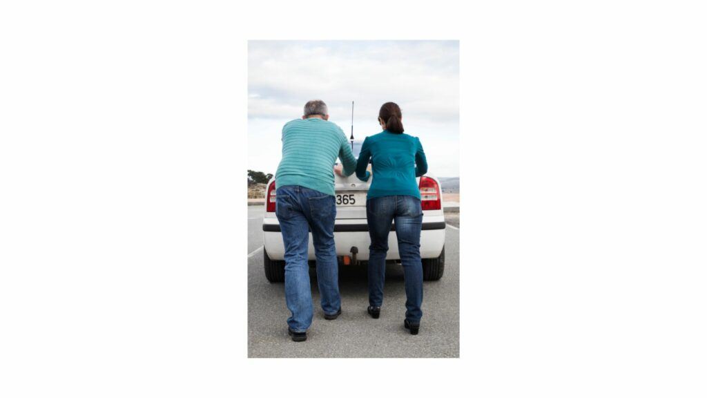 Two people pushing a car