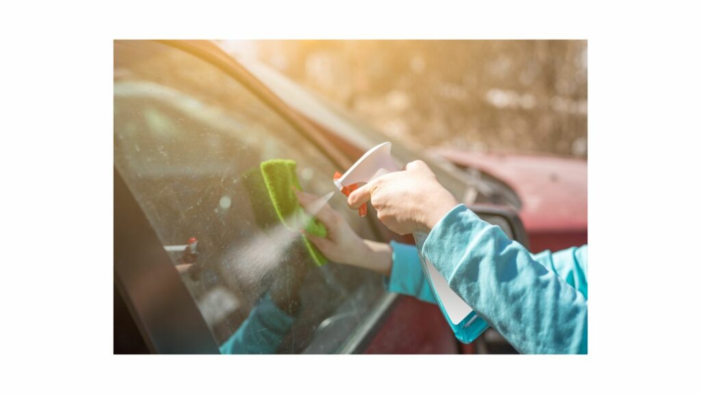 Cleaning a car window with glass cleaner